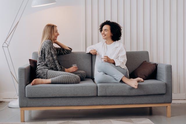 Two people sitting on a couch facing eachother while talking